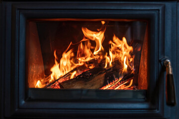 Burning fire in a wood stove fireplace radiates heat, warm home interior,