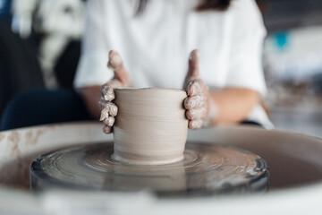 Woman sculpts an object on a potter's wheel