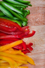 Fresh Three colored bell peppers julienne cut on wooden surface