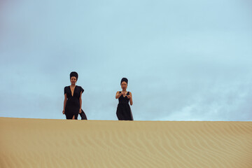 Two woman seen walking on top of sand dune