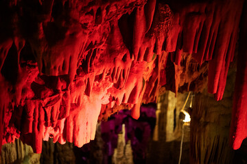 red abstract background of stalactites, stalagmites and stalagnates in a cave underground, horizontal