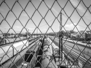 Mesh rabitza in front of the railway station. Selective focus, defocused, film grain. Background image. Black and white.