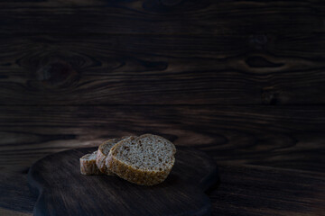 Slices of loaf of rye flour on a dark wooden background. Natural food, bread