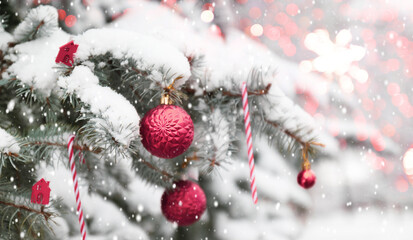 Fototapeta na wymiar Beautiful Christmas tree outdoor with pink xmas balls, snow, lights bokeh around, and snow falling, Christmas atmosphere.