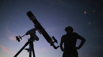 Silhouette of a man, telescope and countryside under the starry skies.