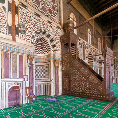 Colorful decorated marble wall with engraved Mihrab - niche - and wooden Minbar - Platform - at...