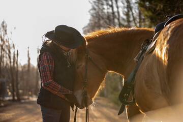 Cowgirl with horse at sunset