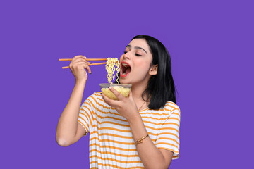 foodie girl eating noodle over purple background indian pakistani model 