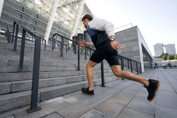 Fototapeta na wymiar Sportive man training outdoors, running on steps