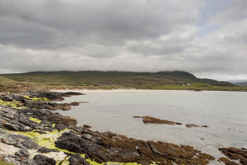 Ragged stone coast line and mountains under low cloudy sky, Silver strand, county Mayo, Ireland. Irish nature background and scenery.