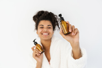 Young afro american woman showing bottle with cosmetics on camera