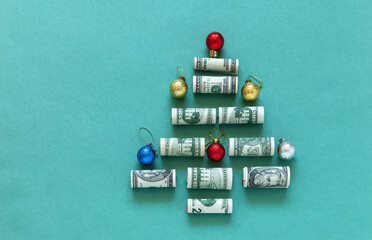 Unusual Christmas tree made of twisted American dollars banknotes on green background. Concept for Christmas payments and annual budget planning. Financial background. Copy space, flat lay