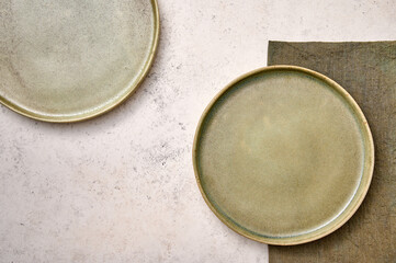 Two green plates with napkin on white textured background. Design concept, copy space