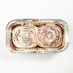 Fresh cinnamon roll bun in baking form isolated on white background