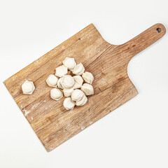 Obraz na płótnie Canvas Raw handmade dumplings on wooden cutting board isolated on white background