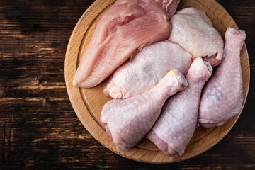 Raw chicken meat: fillet, things and legs on dark wooden background.