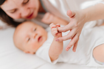 in focus small baby's hand and mother's hand on white sheet. mom and newborn. 