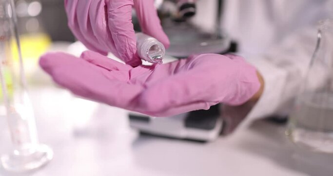 Scientist chemist in protective gloves pouring liquid metal into hand in laboratory closeup 4k movie slow motion