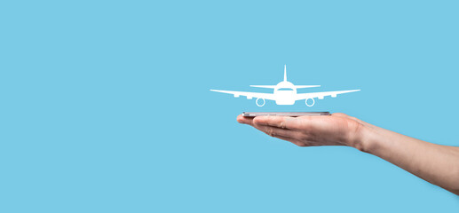 Male hand holding plane airplane icon on blue background. Banner.nline ticket purchase.Travel icons about travel planning, transportation, hotel, flight and passport.Flight ticket booking concept.