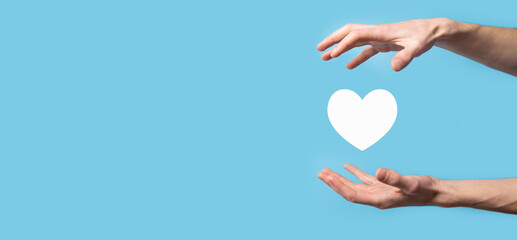 Male hand holding heart , like icon on blue background. Kindness, charity, pure love and compassion concept.Banner with copy space