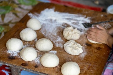 Female Hands Of Baker Rolls Dough In Flour On Wooden Board On Table With A Rolling Pin, In Bakery Shop, Woman Making Pizza Using Traditional Recipe At Home.
