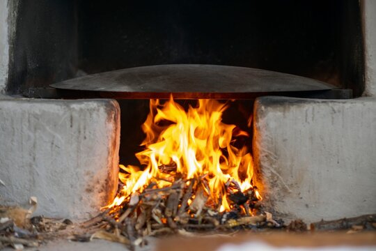 In the oriental courtyard, a fire burns in a medieval stove. lit the firewood to bake bread
