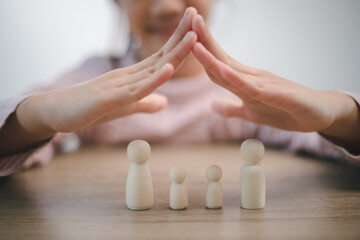 Protecting Hands Over wooden Family, Family Protection And Care Concept, family home, foster care, homeless charity support concept, family mental health, international day of families
