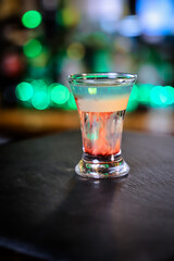 In the glass, the cocktail is brown-red, the top is white and the top is emerald, which is set on fire, the layers are not mixed.
