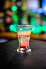 In the glass, the cocktail is brown-red, the top is white and the top is emerald, which is set on fire, the layers are not mixed.