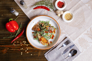 On a dark countertop, a light linen napkin, on a cutting board  Salad with mussels, rucola, red caviar, shrimps in a round dish, cutlery, pepper-salt steam, whole red pepper, hot pepper pod