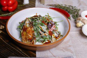 On a dark countertop, a light linen napkin, on a cutting board  Salad with mussels, rucola, red caviar, shrimps in a round dish, cutlery, pepper-salt steam, whole red pepper, hot pepper pod