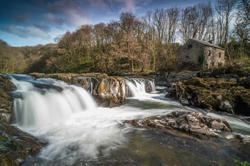 Cenarth Falls, Pembrokeshire. An autumn day, the waterfall is full. Slow shutter speed to smooth out the water