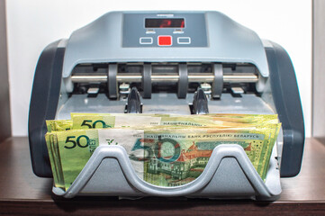 Belarusian rubles banknotes in currency Counting Machine. Front view of the shelf. Selective focus.