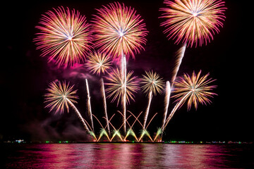 Amazing beautiful colorful fireworks display on celebration night, showing on the sea beach with multi color of reflection on water	
