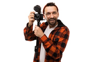 young blogger in a red shirt hat in a black red cage with a video camera on a white background