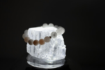 A bracelet made of natural stones of different colors lies on a large transparent stone