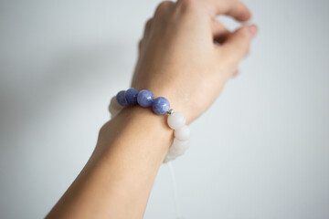 Bracelet with natural stones of different colors on a beautiful hand of a young girl on a white background