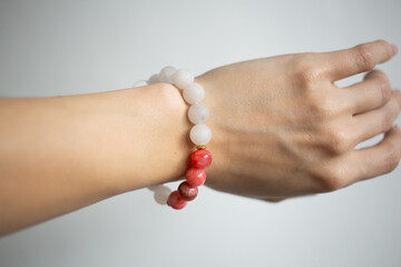 Bracelet with natural stones of different colors on a beautiful hand of a young girl on a white background