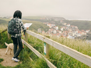 Female hiker with dog looking at map in landscape