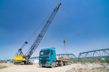 Fototapeta na wymiar The crane loads the metal structures onto the truck