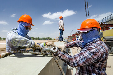 Workers prepare steel for loading. The brigadier does not look.