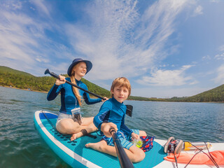 Fototapeta na wymiar happy family of two, mother and son, enjoying stand up paddling during summer vacation