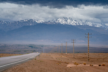 Compressed shot of long straight Rayen road with electric poles along, leading to Rayen city in...