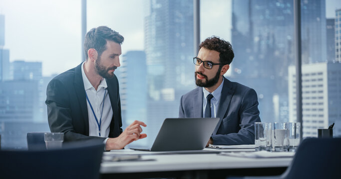 Businesspeople in Office: Business Meeting of Two Businessmen Using Laptop Computer and Talking. Tech CEO and Executive Director do Brainstorming for Digital e-Commerce Software Investment Solution