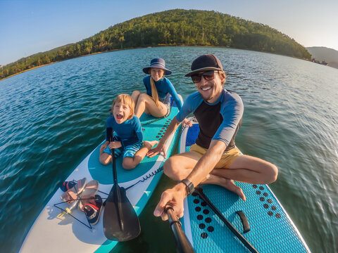 happy family of three, dad, mom and son, enjoying stand up paddling during summer vacation