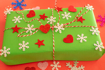 green covered gift wrap on red background. decorated with stars, hearts, snowflakes. new year concept.