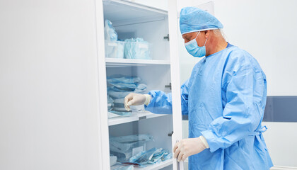 Arzt in Schutzkleidung am Schrank mit Arzneimitteln