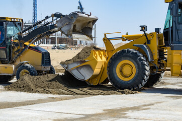 Fototapeta premium Yellow tractors help each other. Construction in the background.