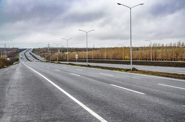 A new road with a dividing strip and lighting poles. Road construction.