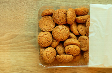 Small delicious amaretto cookies in a package on a wooden table.